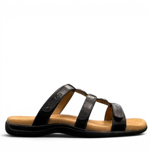 Taos Prize 4 black leather slide sandals with adjustable hook and loop straps and cushioned foot bed. Photo of outside side view.