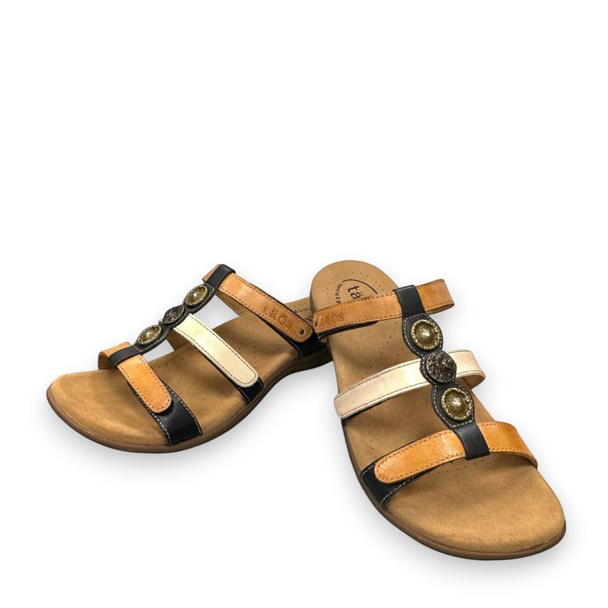 Taos Prize 4 tan multi leather slide sandals with adjustable hook and loop straps and medallion hardware. Photo of front view.