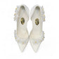 Ticky white pointed-toe high heel pump featuring delicate floral embellishments with crystal accents. Photo of upper view.