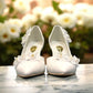 Ticky white pointed-toe high heel pump featuring delicate floral embellishments with crystal accents. Photo of front view.